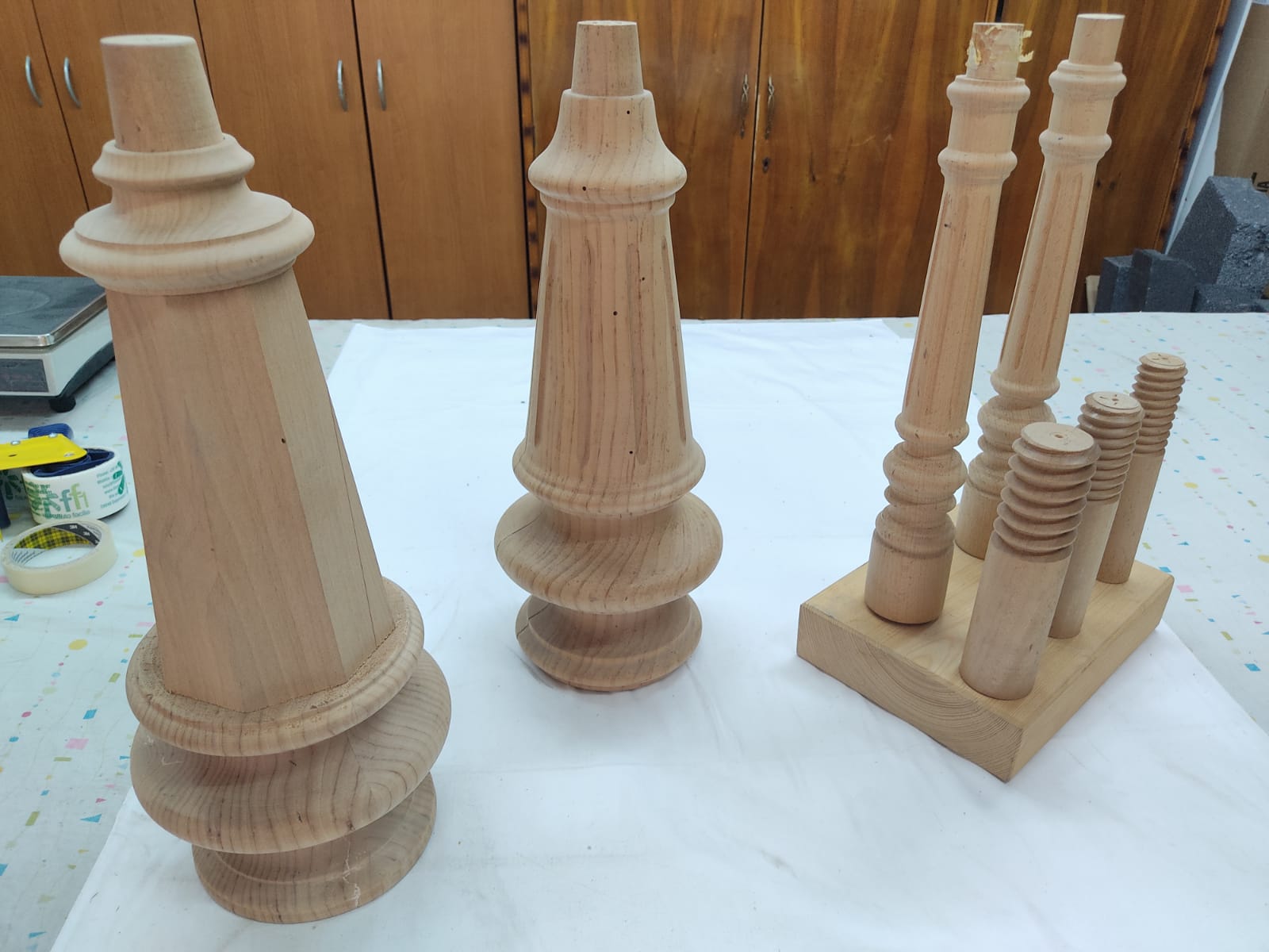 Gambe di pianoforte appena tornite in legno chiaro, allineate sul banco insieme ai piedini di ricambio