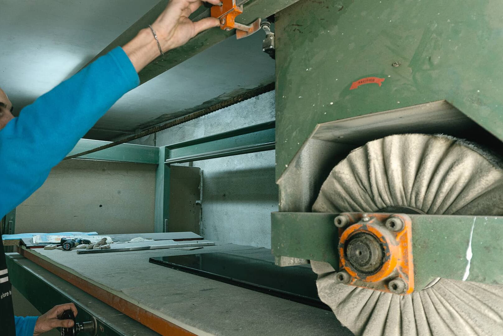 Un operaio del laboratorio regola la spazzolatrice mentre lucida una fascia di pianoforte