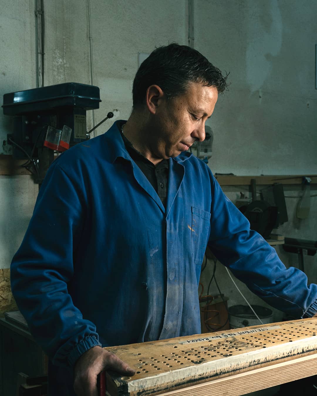 Francesco Alfarano in officina regge il somiere di uno Steinway, con il numero di matricola scritto a mano sul legno